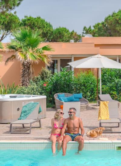 Relaxed couple by the pool with jacuzzi and lounge chairs.