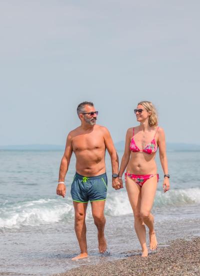 Couple walking on the beach, enjoying a sunny day.