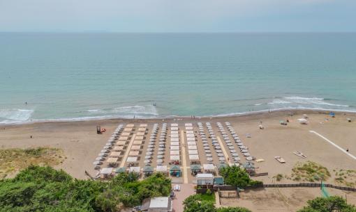 Strand mit Sonnenschirmen und ruhigem Meer, Luftaufnahme.