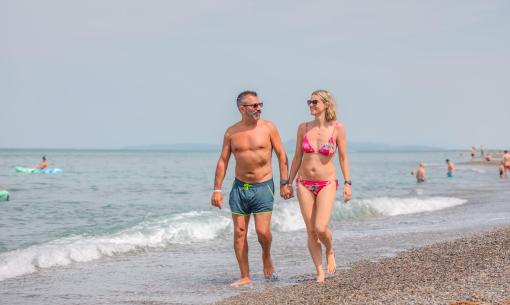 Paar spaziert am Strand und genießt einen sonnigen Tag.