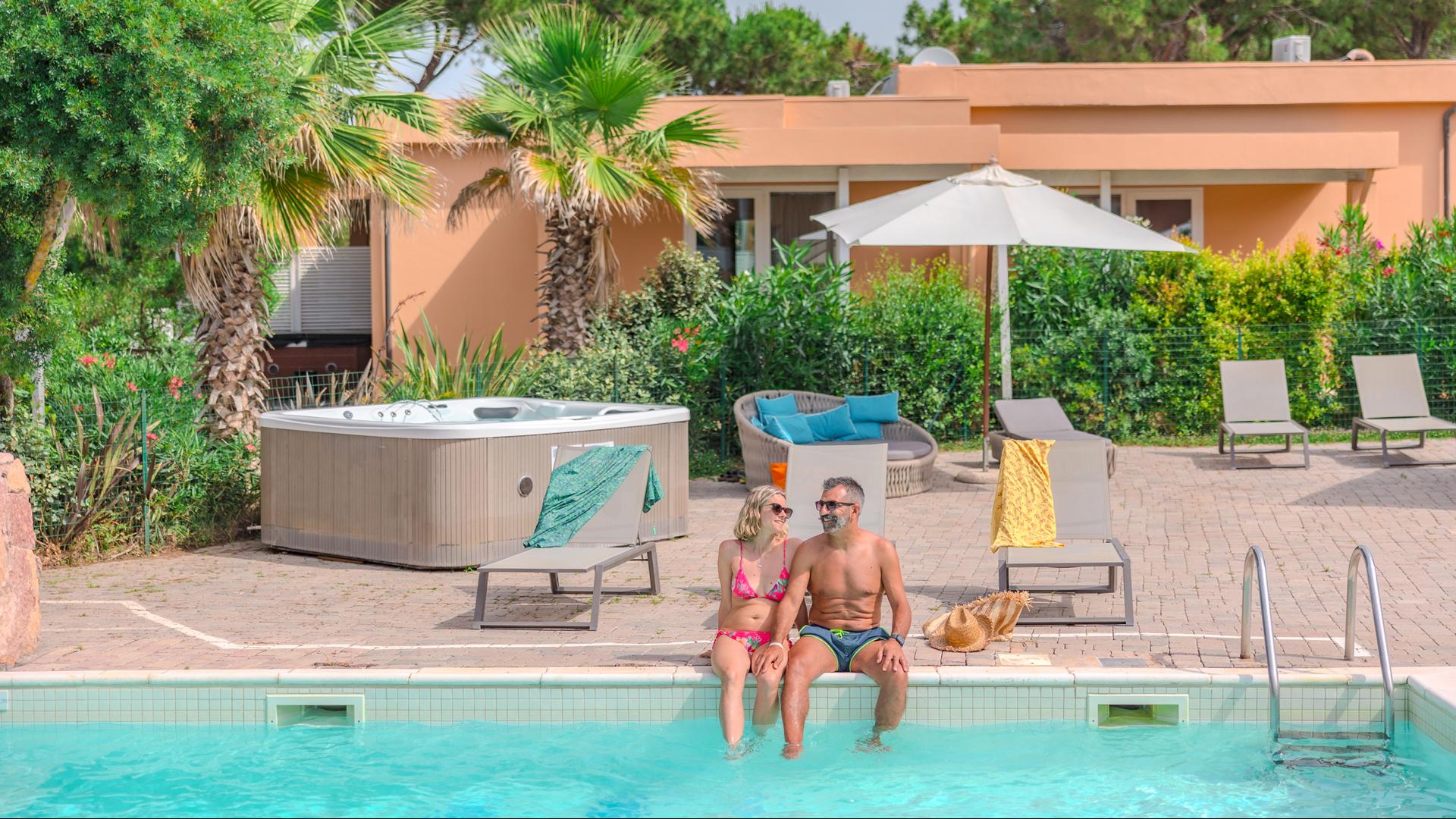 Relaxed couple by the pool in a tropical setting.